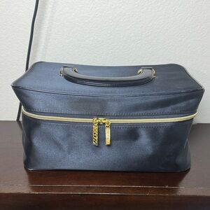 This is a black Estée Lauder satin travel bag with gold zipper.